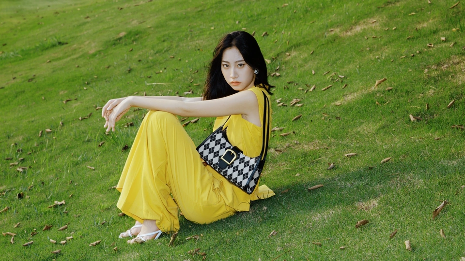 一位穿着黄色连衣裙的年轻女子在绿草地上