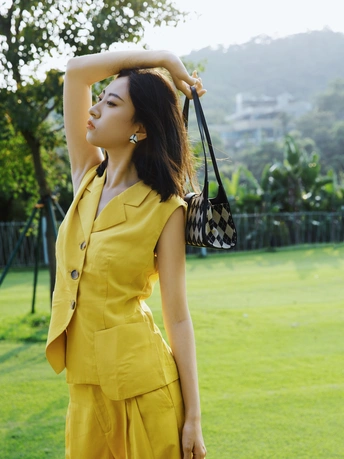 一位穿着黄色连衣裙并拿着一个包的女人