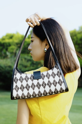 一位穿着黄色连衣裙的女性 holding a黑色和白色钱包