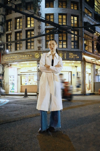 一个穿着白大褂的女人站在夜晚的街道中央 双手交叉