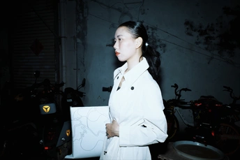 一个穿着白色风衣的女人在一个黑暗的房间里拿着一张纸