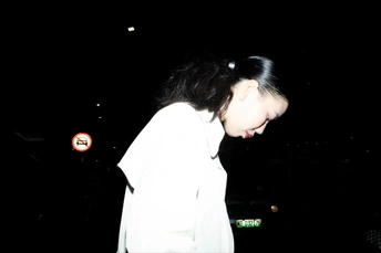 一个年轻女孩在晚上骑着白色滑板车在街上