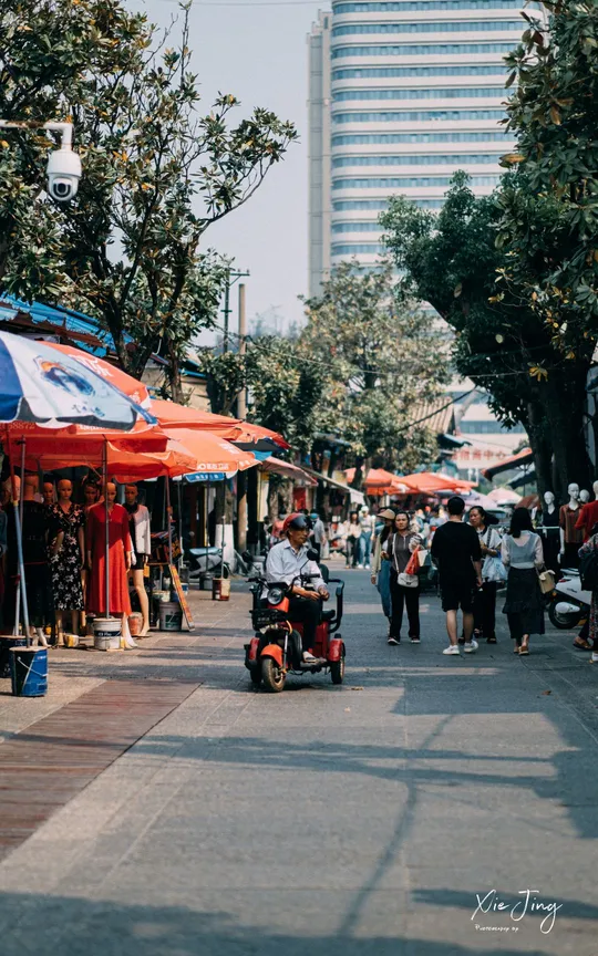城市人行道上有行人行走 摩托车在街上行驶。