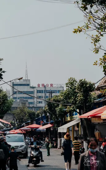 人们在市场附近的一条街道上走 停着的车。