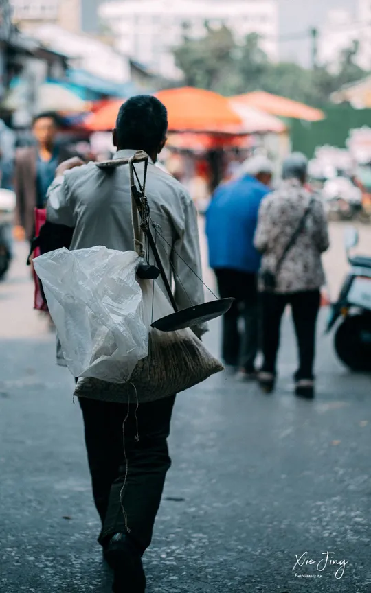 一个人拿着塑料袋走在拥挤的街道上