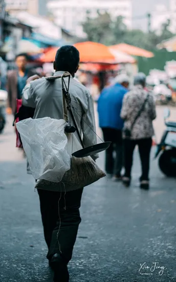 一个人拿着塑料袋走在拥挤的街道上