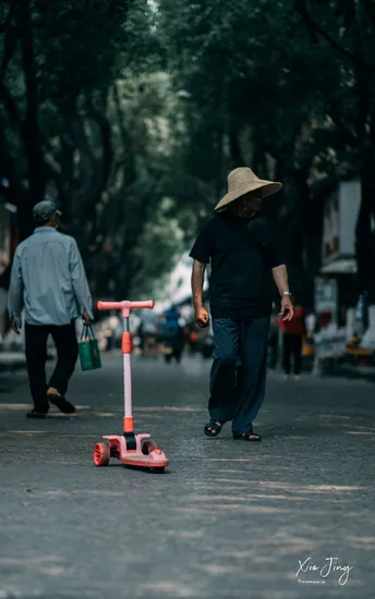 一个戴帽子的男人骑着红色的滑板车沿着街道滑行