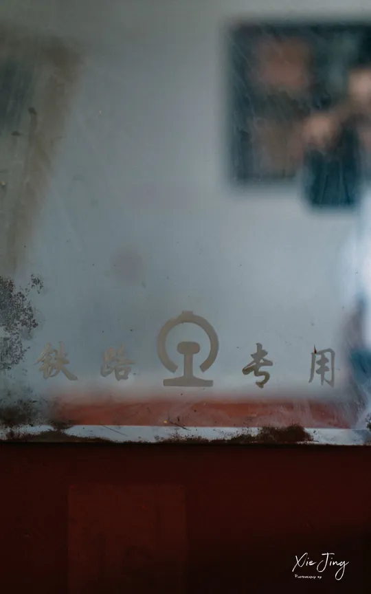 一个通过脏窗户拍摄 玻璃上有中国符号反射的男人