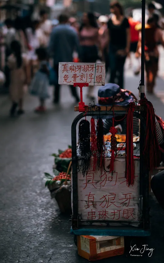 一个坐在街边 在人们旁边打着伞的男人