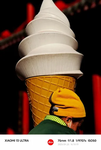 一个人戴着黄帽子 头上顶着一个冰淇淋 cone。