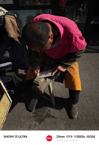 一位男子在街头用砂纸打磨一块木头