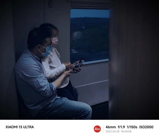 一个戴口罩的男子坐在火车上 凝视着黑暗的窗户。