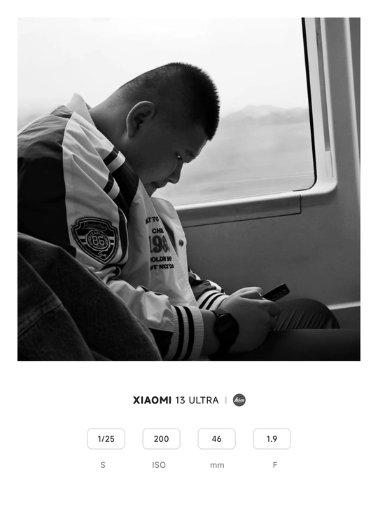 一张黑白照片 一个年轻的男孩坐在火车上 正在看窗外。