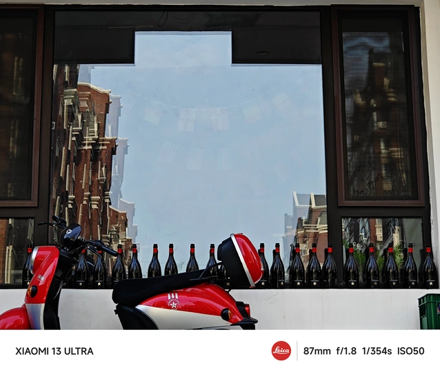 一辆红色的摩托车停在靠近建筑物的窗户前