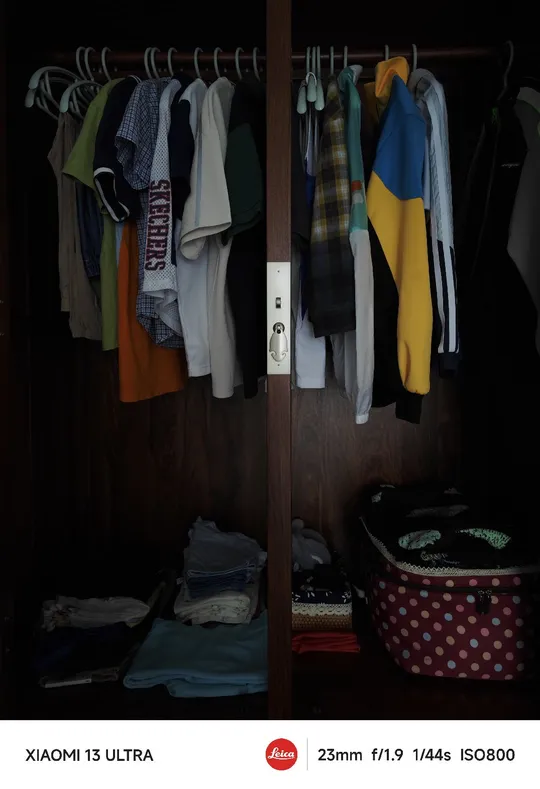 一个黑暗房间里的开放式衣柜 挂着衬衫和毛衣。