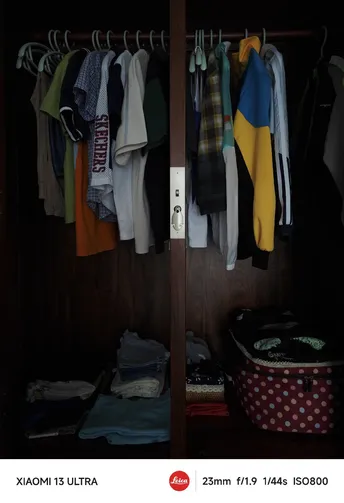 一个黑暗房间里的开放式衣柜 挂着衬衫和毛衣。