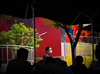 人们戴口罩坐在遮阳伞下