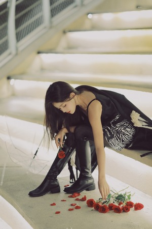 一个穿着黑色连衣裙和高跟鞋的年轻女子正在插红玫瑰。