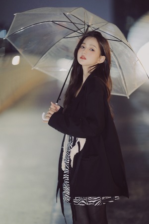 一个穿着黑色外套的年轻女子拿着雨伞