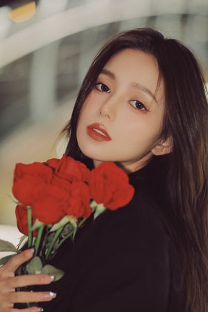一位美丽年轻的女子手里拿着一束红色的玫瑰花。