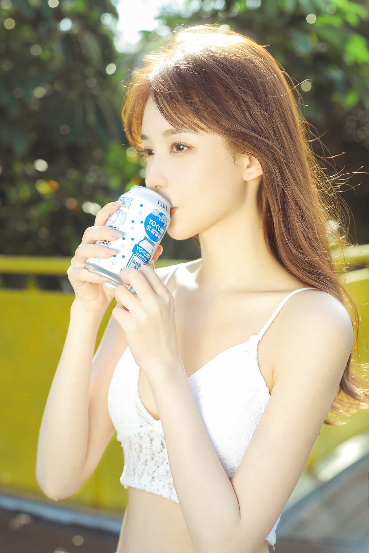 一个美丽的年轻女子手持一个白色杯子在户外喝水或咖啡