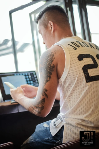 一名有纹身的男子正在看手机和笔记本电脑