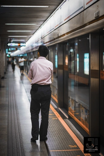 一个穿粉色衬衫的男子站在地铁站旁边的一辆火车上