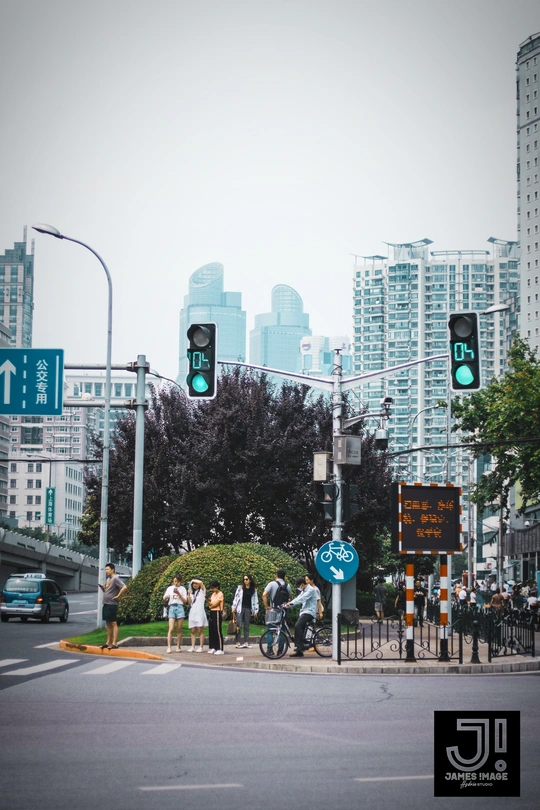 人们穿越人行横道 背景是绿灯和建筑物。