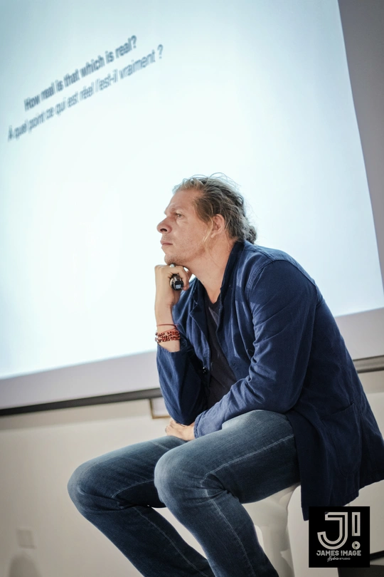 一个坐在椅子上的男人 前面有一个屏幕 屏幕上有一张人的图片。