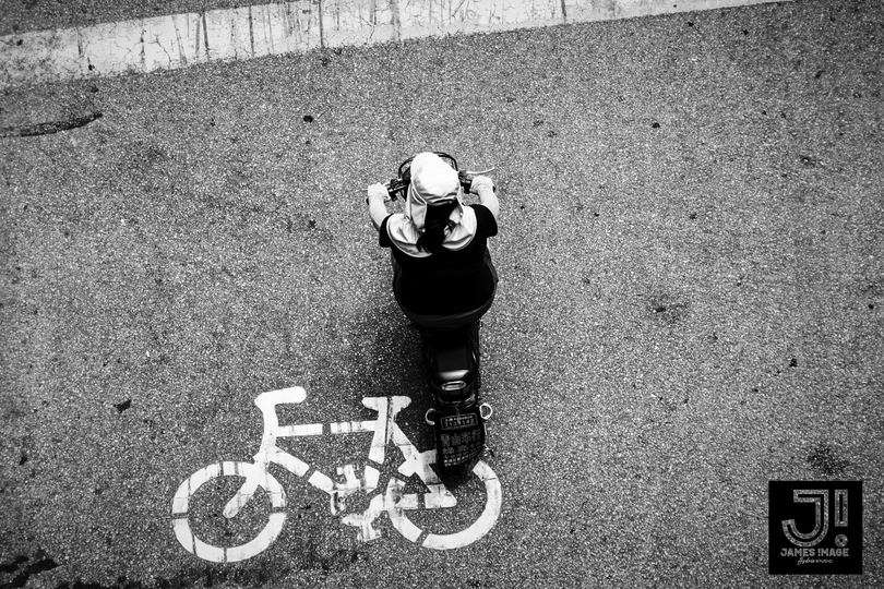 一张黑白照片 一个人站在人行道上 旁边有一个停车计数器和地上的涂鸦 一辆自行车。