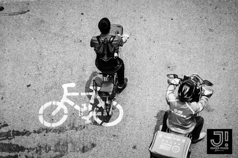 一些人在街上站在一个骑自行车的人旁边