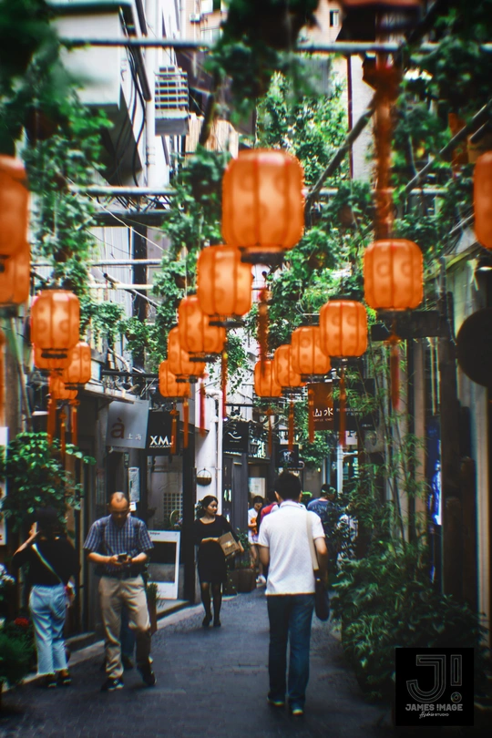 人们走在挂满灯笼的狭窄巷子里