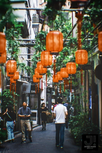 人们走在挂满灯笼的狭窄巷子里