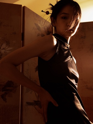 一位穿着黑色连衣裙的年轻女子站在一面墙前