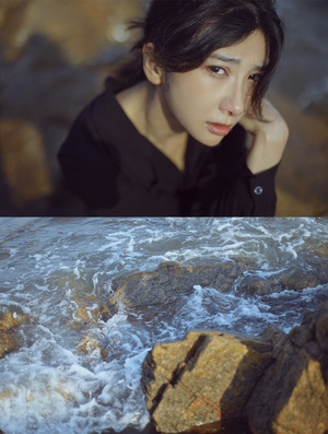 一位年轻女子坐在靠近海洋的岩石上