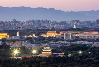 暮色或夜晚的城市 天际线点亮 背景是山脉。