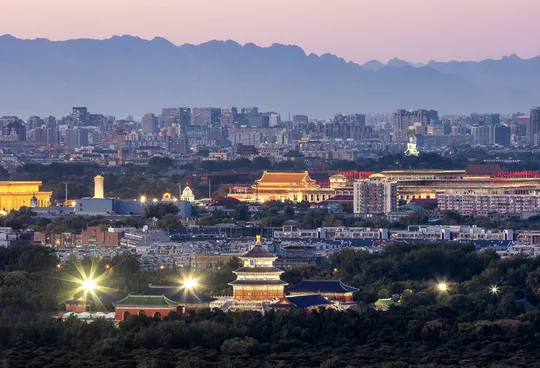 暮色或夜晚的城市 天际线点亮 背景是山脉。