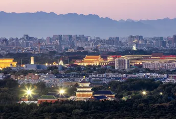 暮色或夜晚的城市 天际线点亮 背景是山脉。