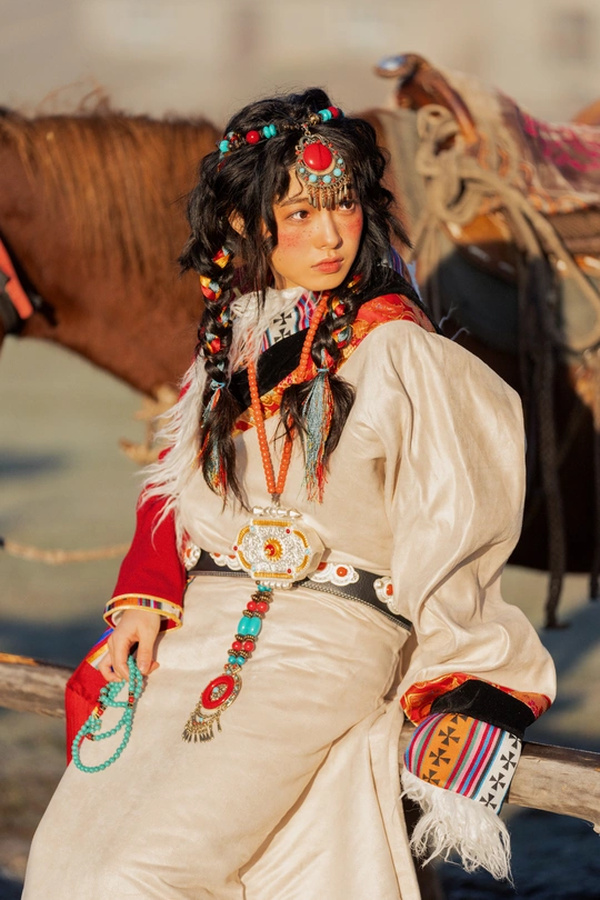 一位穿着传统服装的年轻女子坐在 fence 旁边的一匹棕色马旁边。