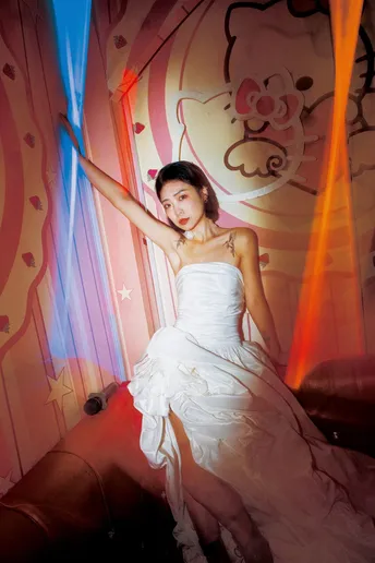 一位穿着白色婚纱的年轻女子在一个充满鲜艳颜色的房间里 墙上有一盏蓝色的灯光 正在摆姿势。