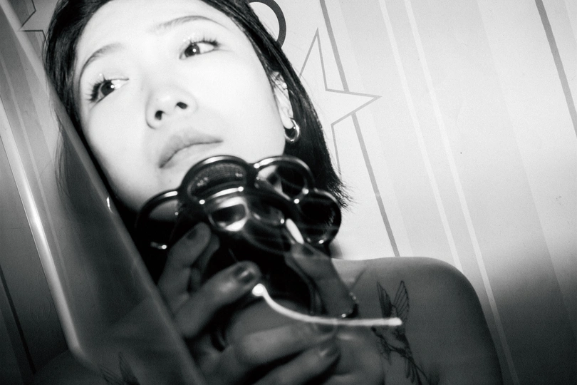 一张黑白照片 女孩手持剪刀和酒杯站在镜子前