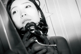 一张黑白照片 女孩手持剪刀和酒杯站在镜子前