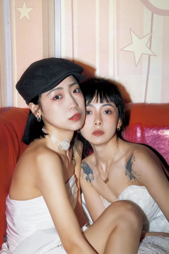 两位戴帽子的女士在红色沙发上为拍照姿势