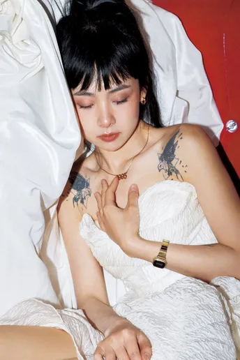 一个有纹身的年轻女子坐在一张白色床上