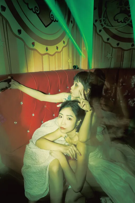 几个女孩坐在一个昏暗的房间里的一张红色沙发上