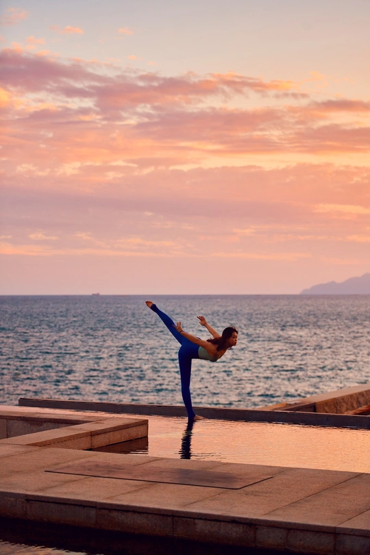 晨曦或夕阳时分在海洋或海边的台阶上练习瑜伽的年轻女子