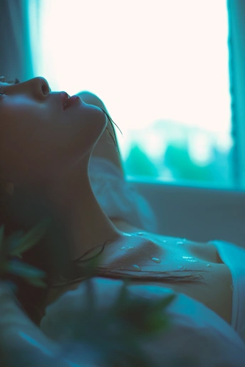 一位年轻女子躺在蓝色的灯光透过窗户照进来的房间里。