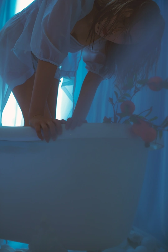 一个年轻女孩在一个带有蓝色灯光和有花的水槽浴缸里洗澡