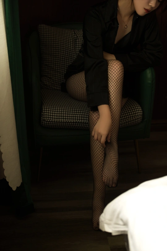 一个穿着黑色连衣裙和紧身裤的年轻女子坐在椅子上