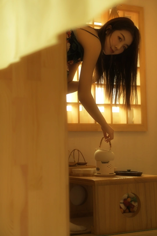一位年轻女子在厨房里往杯子里倒水